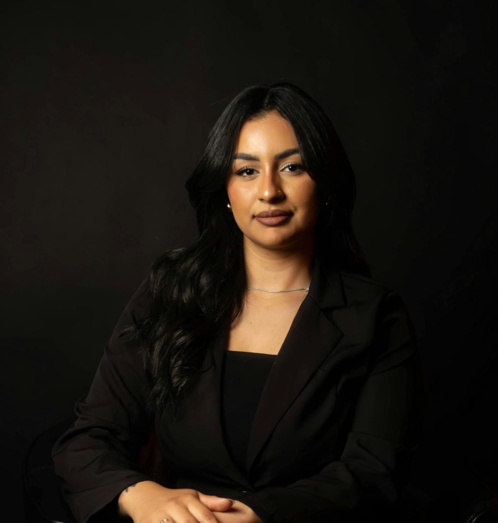 Portrait of a confident business woman in formal attire against a dark background.